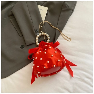 Detail of red satin drawstring bucket bag with pearl embellishments and bow accents
