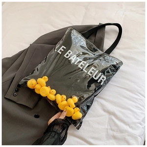 Detail of transparent tote bag featuring yellow rubber ducks and LE BATELEUR print