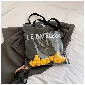 Detail of transparent black tote bag with white text and yellow rubber ducks inside