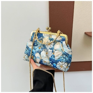 Detailed close-up of blue butterfly embroidery and golden clasp on retro shell bag