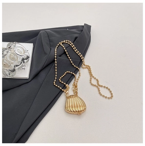 Detailed view of mini golden shell bag with chain on gray blazer fabric background