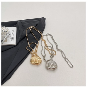 Close-up of gold and silver shell pendants on bead chains with a minimalist book background