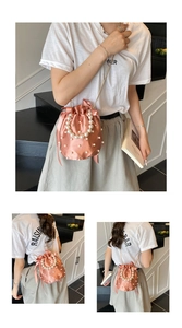 Detail of pink satin bucket bag with pearls, chain strap and elegant bow accent