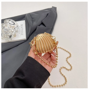 Macro shot of mini metallic gold shell bag with textured surface and delicate bead chain