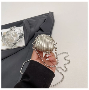 Detail of silver shell-shaped mini bag with metallic texture and sleek ball chain strap