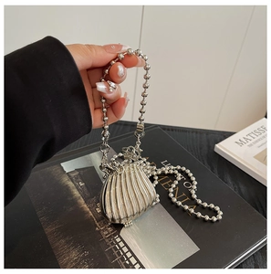 Macro shot of silver shell-shaped mini bag with bead chain on art books background