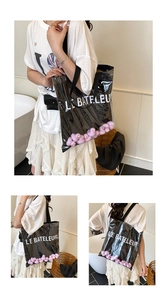 Detail of transparent PVC tote bag featuring pink duck dolls and LE BATELEUR art text