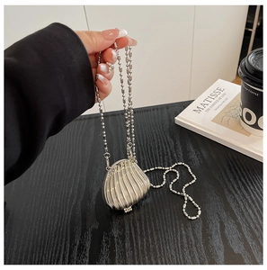 Close-up of a silver shell-shaped metallic mini bag with a beaded chain strap