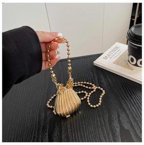 Detailed view of the gold shell-shaped mini metal bag with elegant bead chain strap