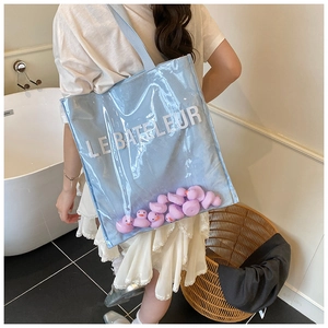Detail of light blue transparent jelly tote bag with purple rubber ducks and lettering