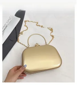 Detail of gold box clutch bag featuring a metallic finish and crystal clasp closure
