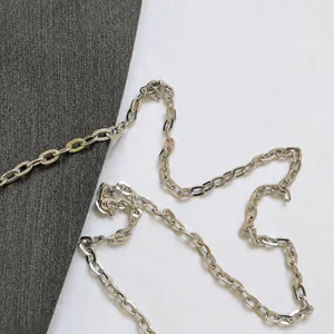 Detailed view of the polished silver metal chain strap on the cylinder bag
