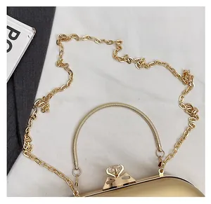 Detail of gold evening clutch featuring a metallic finish, snake handle and crystal clasp