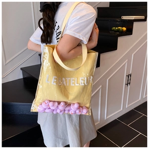 Close-up of clear PVC bucket bag featuring yellow canvas inner pouch and purple duck toys