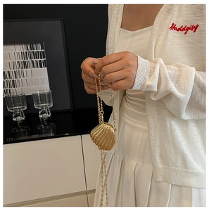 Detail of a mini gold shell bag with metallic texture and sleek golden chain strap