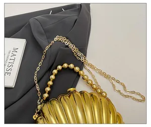 Detail of gold shell-shaped clutch bag with beaded handle and elegant metal chain strap