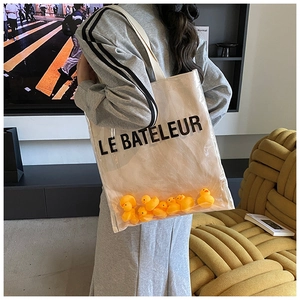 Detail of transparent PVC tote bag with yellow rubber ducks and LE BATELEUR logo text