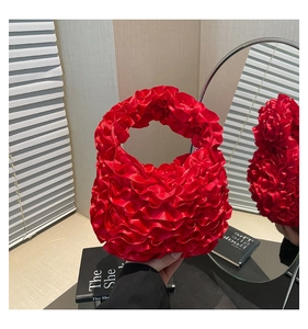 Detailed view of vibrant red ruffled satin handbag with layered pleats and silk texture