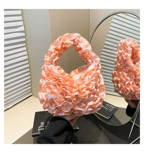 Detailed macro view of pink ruffled satin handbag reflected in a round mirror