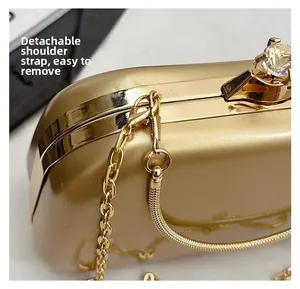 Close-up of golden hard shell evening bag with gemstone clasp and detachable chain