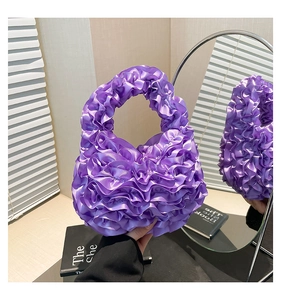 Detail of purple ruffled satin handbag showing layered pleats and silky texture