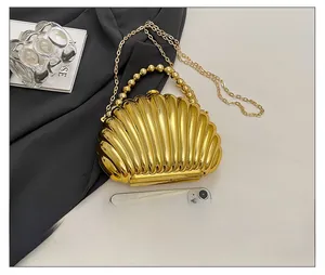 Detailed size view of gold shell evening bag with pearl handle and metal chain strap