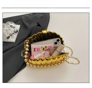 Interior capacity show of golden shell clutch bag with pearl handle and metal chain