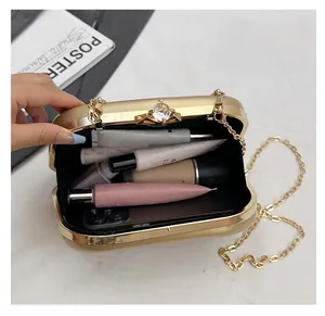 Detailed interior of gold clutch bag with crystal clasp showing phone and cosmetics space