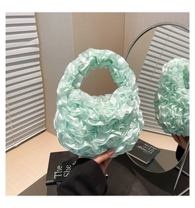 Detailed close-up of mint green pleated satin handbag with ruffled floral textures