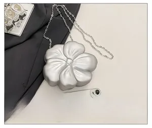 Silver flower-shaped acrylic mini bag with chain strap and size reference to a phone