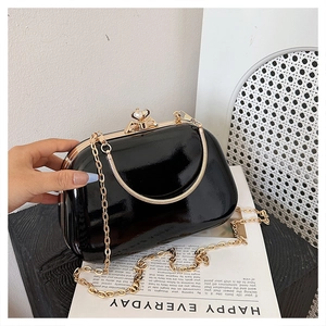 Detail of black patent leather evening bag with heart crystal clasp and gold chain