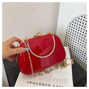 Detail of red glossy evening clutch bag with crystal clasp and gold chain strap