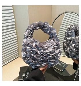 Detailed view of a silver satin scrunchie bag with layered ruffle and soft silk texture