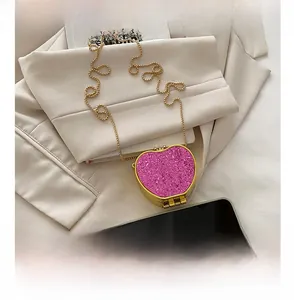 Detailed view of pink glitter heart mini bag with gold chain next to a smartphone