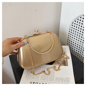 Close-up of golden evening clutch with crystal buckle, metal handle and chain strap