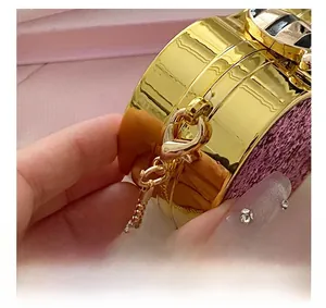 Macro shot of gold metal hardware and pink glitter texture on a luxury chain bag