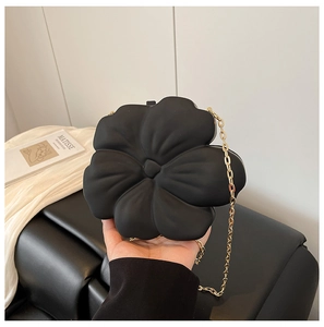 Close-up of black 3D flower acrylic mini bag with a fine gold chain strap in hand