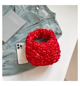 Detail of red pleated handbag with satin sheen finish and ruffled texture layers