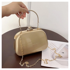 Detail view of a gold metallic evening clutch featuring a large diamond-shaped rhinestone clasp