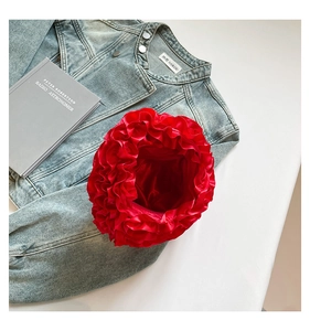 Detail of red floral pleat satin handbag next to denim jacket on a clean background