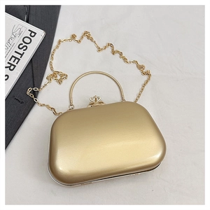 Macro detail of golden metal evening clutch with diamond clasp and round handle