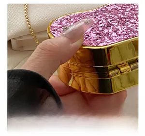 Detail of pink glitter heart-shaped clutch bag with golden chain and metallic frame