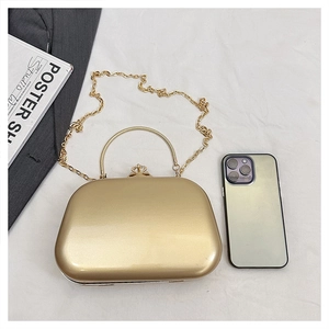 Detail of a gold metallic evening clutch featuring a crystal clasp and chain strap