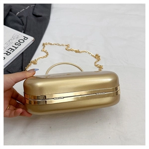 Detail of gold hard shell evening clutch bag with metal handle and detachable chain strap