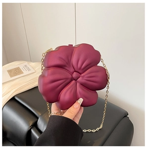 Macro view of burgundy flower-shaped acrylic clutch with gold chain strap detail