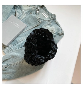 Top view of black satin handbag featuring dense layered ruffles and elegant silk texture