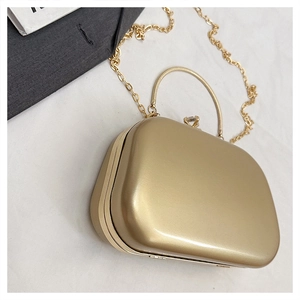 Detail of gold hard shell evening clutch with jewel clasp and detachable chain strap