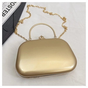 Close-up of gold evening clutch with pearlescent shell, metal handle, and jeweled clasp