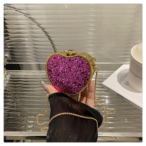 Detail of heart-shaped glitter evening bag with pink sequins and gold metal chain strap