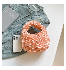 Detail of pink satin pleated handbag with ruffle textures next to a smartphone